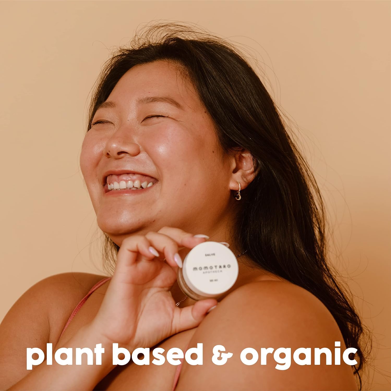 Woman holding a jar with 'plant based & organic' text on a beige background